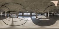 a very large room with lots of columns and arches on the ceiling and an area with windows and lots of concrete flooring