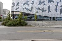 an empty sidewalk near a glass and metal building with windows on it's sides