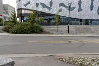 an empty sidewalk near a glass and metal building with windows on it's sides