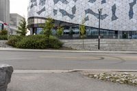 an empty sidewalk near a glass and metal building with windows on it's sides