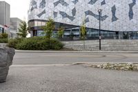 an empty sidewalk near a glass and metal building with windows on it's sides