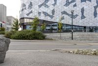 an empty sidewalk near a glass and metal building with windows on it's sides