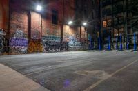 a empty parking lot with graffiti on the walls at night in an old factory complex