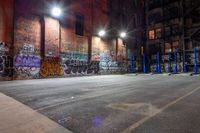 a empty parking lot with graffiti on the walls at night in an old factory complex