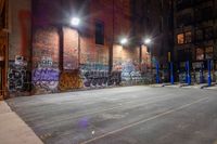 a empty parking lot with graffiti on the walls at night in an old factory complex