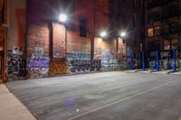 a empty parking lot with graffiti on the walls at night in an old factory complex