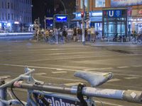 a bunch of bicycles are parked in front of some buildings and people with bikes are waiting to cross the street