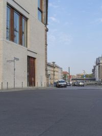 an empty city street with many cars going by it and on to the building, a clock tower stands in the distance