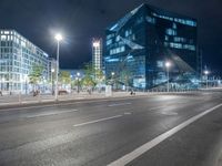 the empty roadway is lined with modern building facades, lights, and empty streets during the night