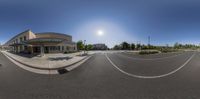 an 360 - degree view of street in front of a building near some bushes and a bench