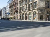 a street is empty and full of people walking and riding bikes nearby buildings and a street light