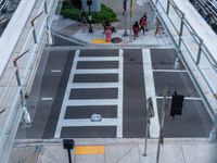 an overhead view of the intersection of an urban street with a pedestrian crossing and cars