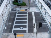 an overhead view of the intersection of an urban street with a pedestrian crossing and cars