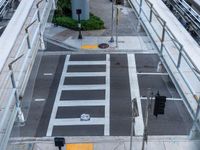 an overhead view of the intersection of an urban street with a pedestrian crossing and cars