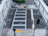 an overhead view of the intersection of an urban street with a pedestrian crossing and cars