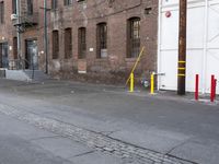 a street with some tall brick buildings in the background, next to a yellow fire hydrant