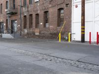a street with some tall brick buildings in the background, next to a yellow fire hydrant