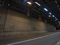 an empty street near a tunnel and buildings in the night time, with no people standing on it