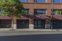 two garages on the side of a street with a tree and an open parking space