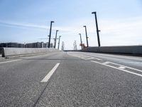 a street going under some tall poles and wires in the air on a clear day