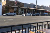 cars are parked near the curb on a street corner and two benches are facing towards the camera