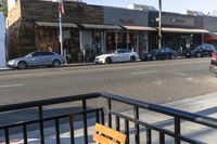 cars are parked near the curb on a street corner and two benches are facing towards the camera