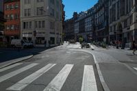 a street with several buildings on both sides and a motorcycle rider on the road behind it