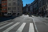 a street with several buildings on both sides and a motorcycle rider on the road behind it