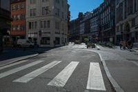 a street with several buildings on both sides and a motorcycle rider on the road behind it