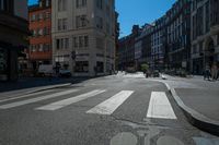 a street with several buildings on both sides and a motorcycle rider on the road behind it