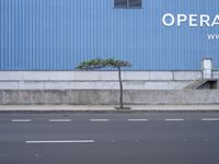 an empty street with cars parked on it beside a building with an overhang of operation words