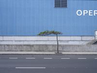 an empty street with cars parked on it beside a building with an overhang of operation words