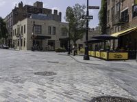 a stone paved street with an open space for patrons to relax at the bar's windows