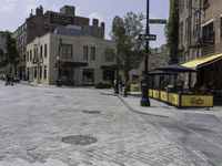 a stone paved street with an open space for patrons to relax at the bar's windows