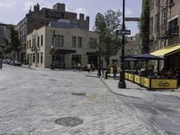 a stone paved street with an open space for patrons to relax at the bar's windows