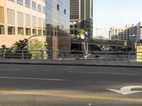 the view of a street where you can find a bus and cross a small bridge