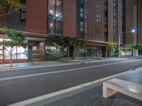 a long and narrow street has a wooden bench in front of the building where it belongs