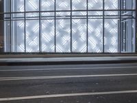 a building has a glass front in a city street, with greenery in front