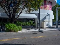 a man riding a skateboard across the street from a shop with trees on it