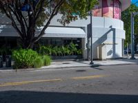 a man riding a skateboard across the street from a shop with trees on it