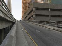 the car is traveling along the empty road by the large city buildings in the distance