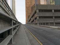 the car is traveling along the empty road by the large city buildings in the distance