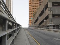 the car is traveling along the empty road by the large city buildings in the distance