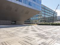 a building with many windows next to a sidewalk with a stone block pattern on the outside