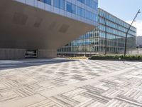 a building with many windows next to a sidewalk with a stone block pattern on the outside