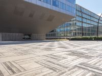 a building with many windows next to a sidewalk with a stone block pattern on the outside