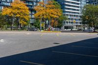 a bus stop sign in a parking lot near a tall building with trees and cars