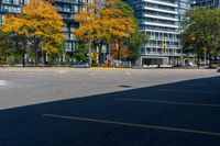 a bus stop sign in a parking lot near a tall building with trees and cars