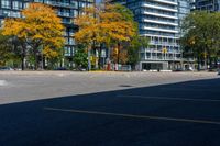 a bus stop sign in a parking lot near a tall building with trees and cars