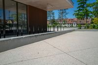 a skateboard rests on the wall near a park with trees in the background and an office